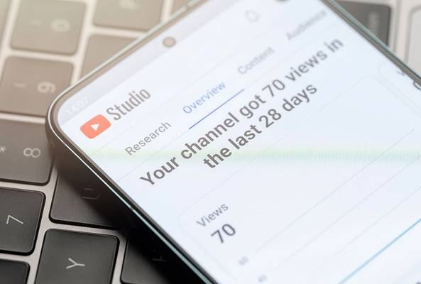 Smartphone showing YouTube Studio analytics with 70 views in the last 28 days