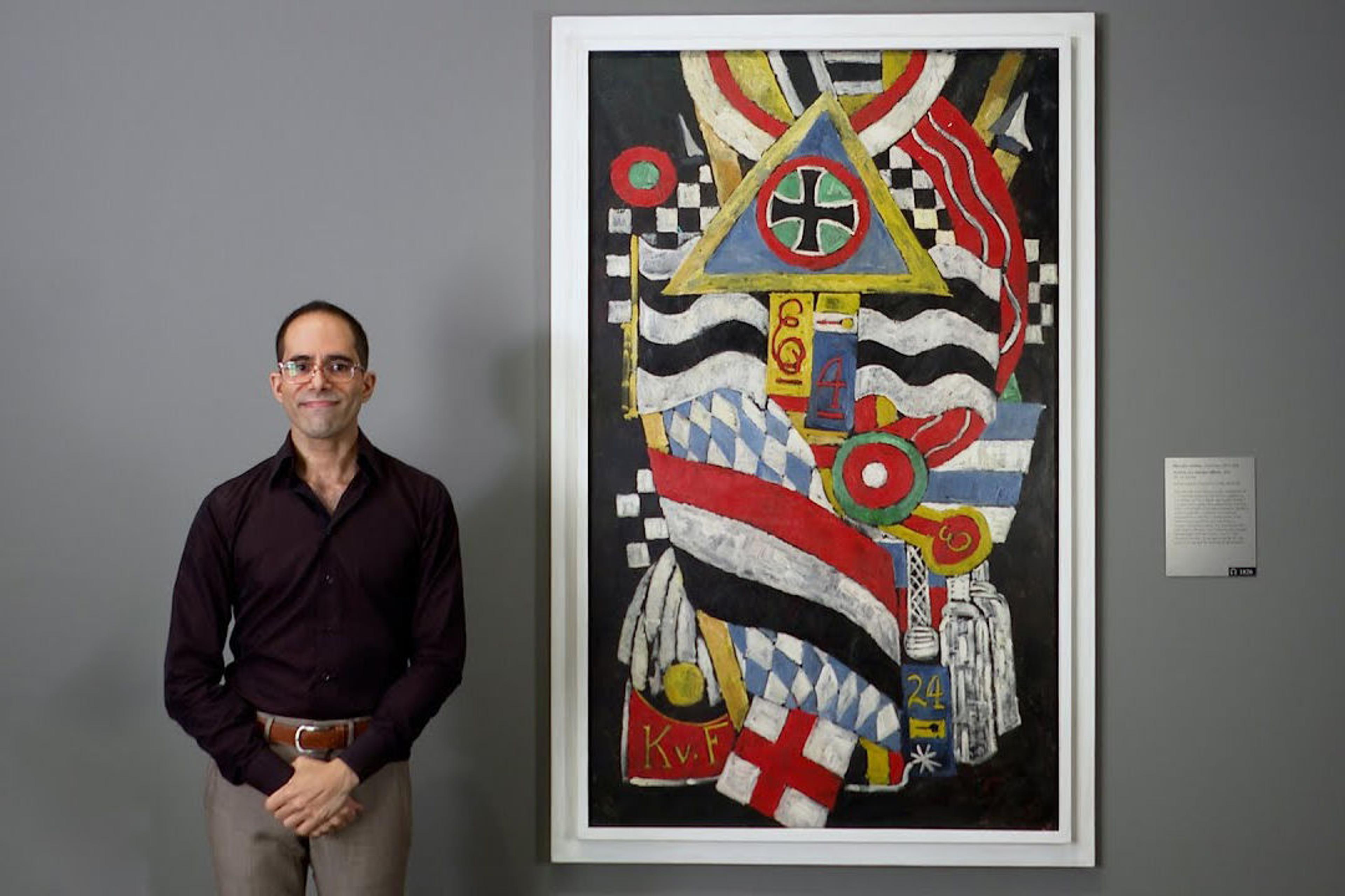 Art Historian and Met educator Emmanuel von Schack standing beside Marsden Hartley painting, "Portrait of a German Officer"