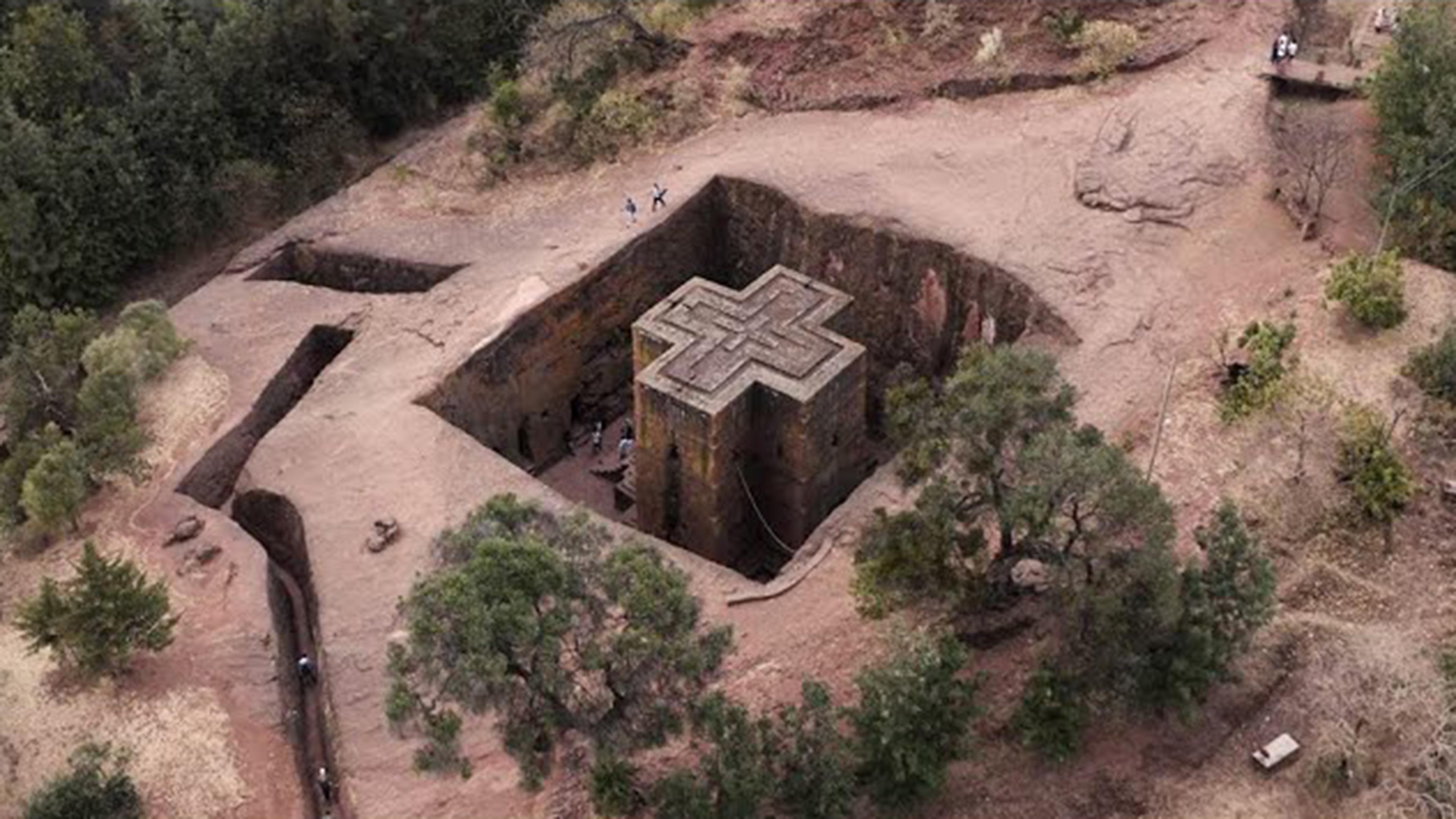 Aerial perspective of an archaeological dig, with a formation structure shaped like a plus sign in the center of a large pit
