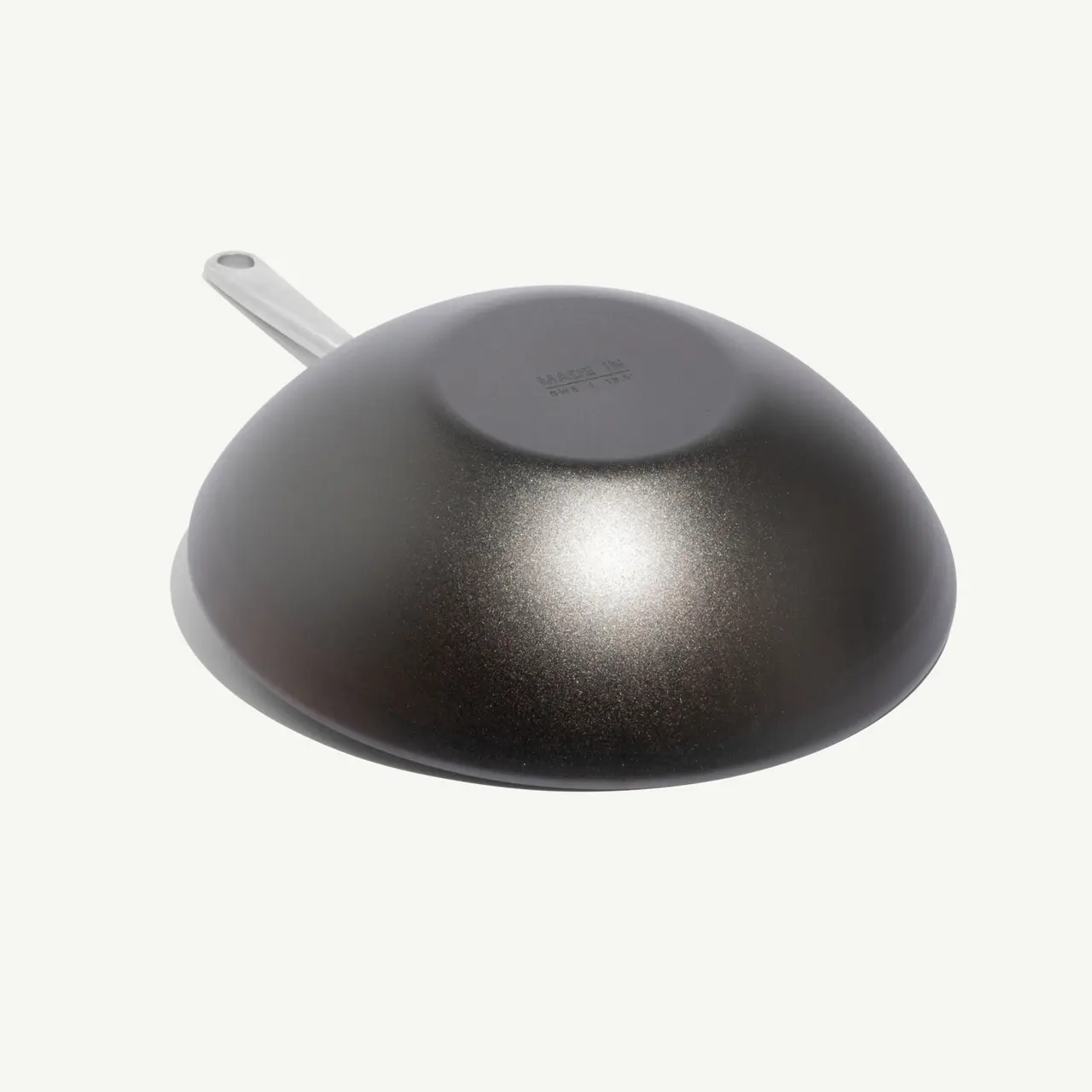 A dark, rounded cooking pan with a metallic finish and a long handle.