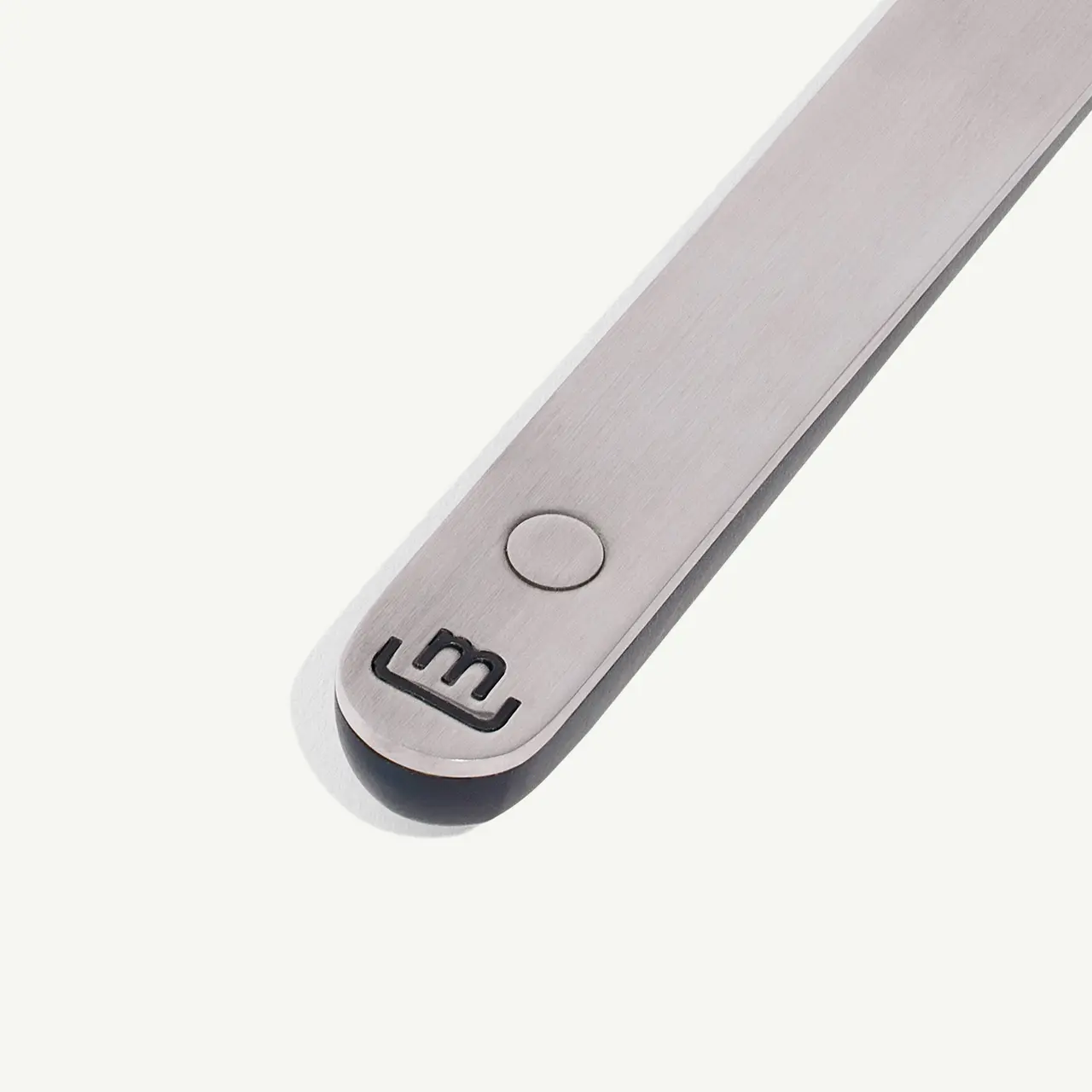 A close-up of a stainless steel tool with the number 3 engraved at one end and a circular indent near it.