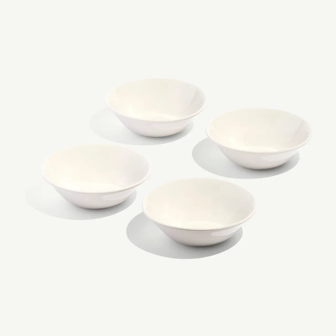 Four white bowls are arranged in a neat group on a plain background.