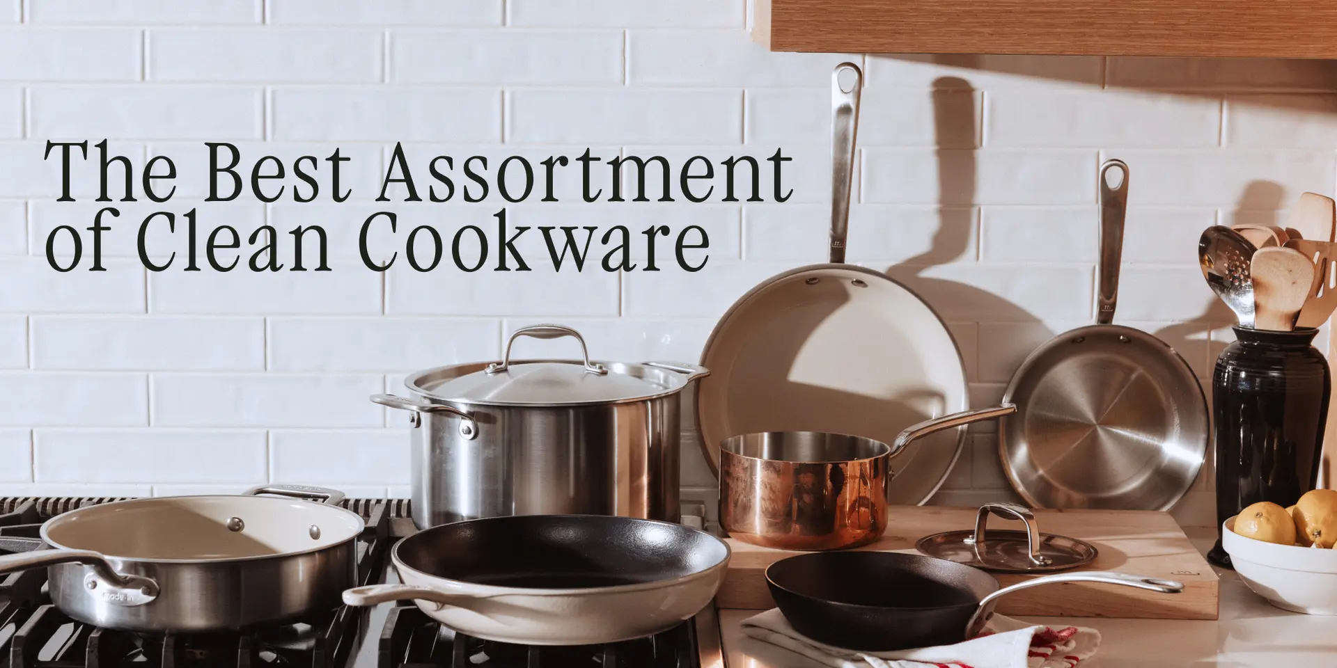 An organized display of various clean cookware items is arranged on a kitchen countertop next to a stovetop.