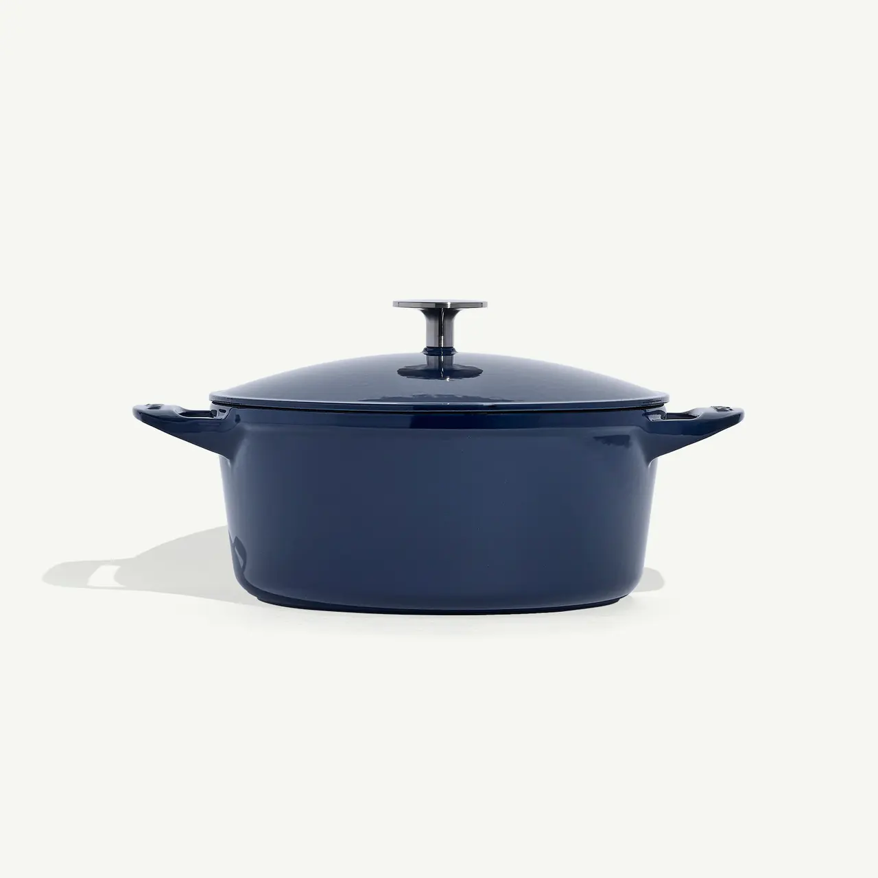 A dark blue oval Dutch oven with a lid and side handles.