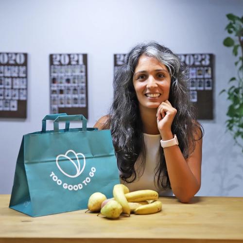 a woman is sitting at a table with a bag of bananas and pears .