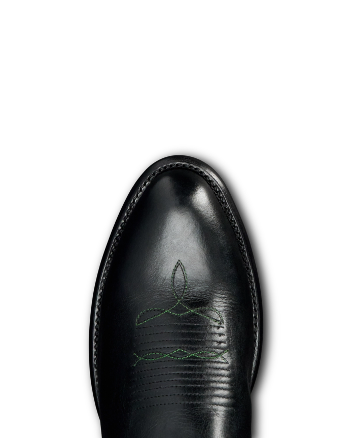 Top view of a shiny black leather shoe with green decorative stitching on the toe, set against a black background.