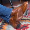 Man in jeans wearing ostrich boots, crossed at the ankles